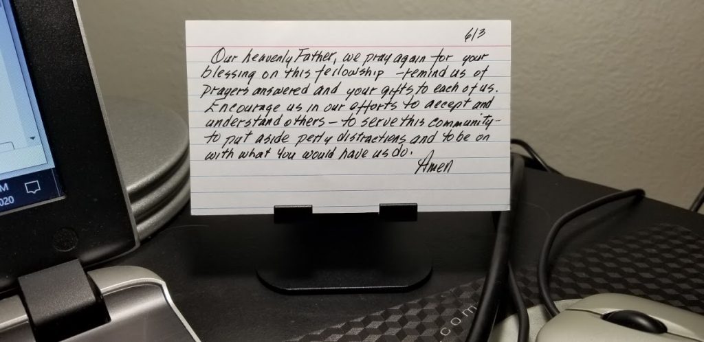 index card on phone stand at desk